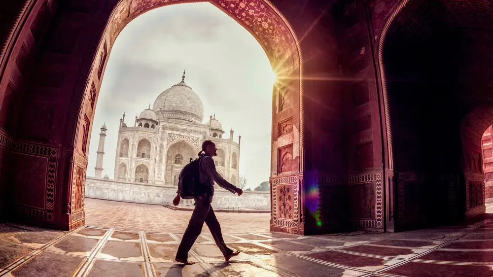 Tourist with backpack walking in the mosque arch near Taj Mahal in Agra